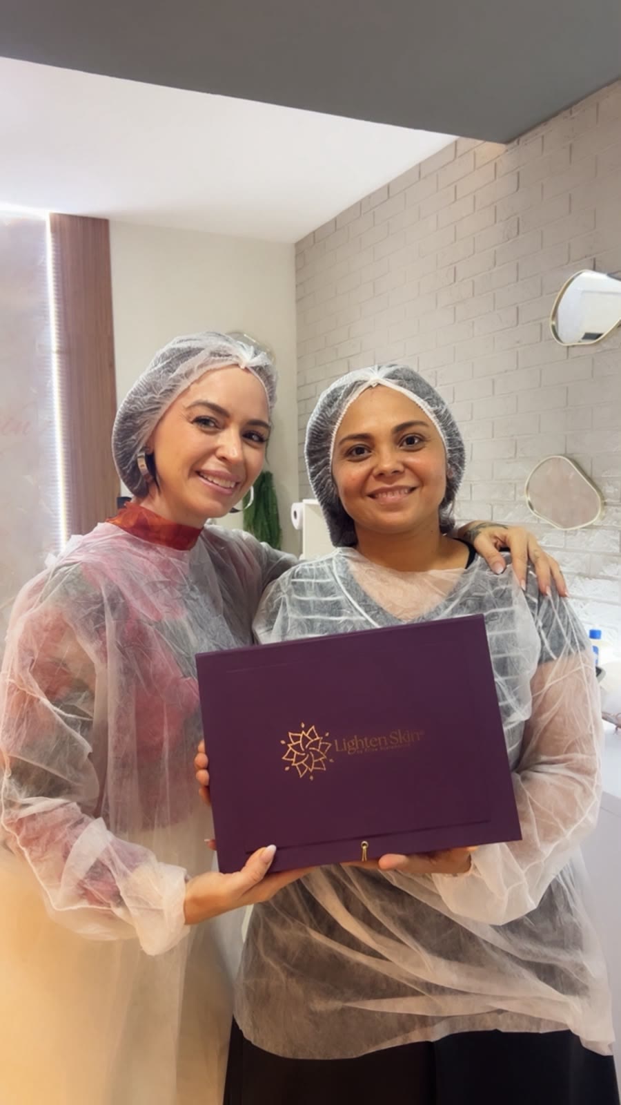 Erica com aluna segurando a caixa Lighten Skin