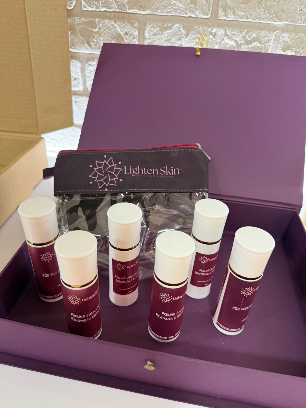 Kit Lighten Skin aberto, com frascos e necessaire sobre a caixa roxa