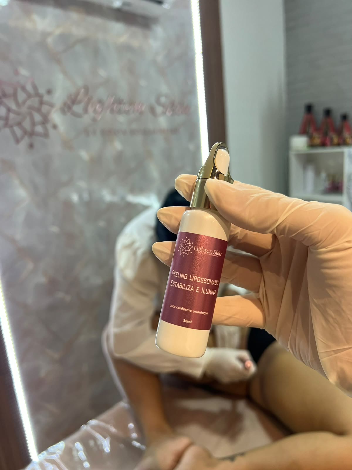 Frasco Lighten Skin diante do painel da marca na sala de atendimento